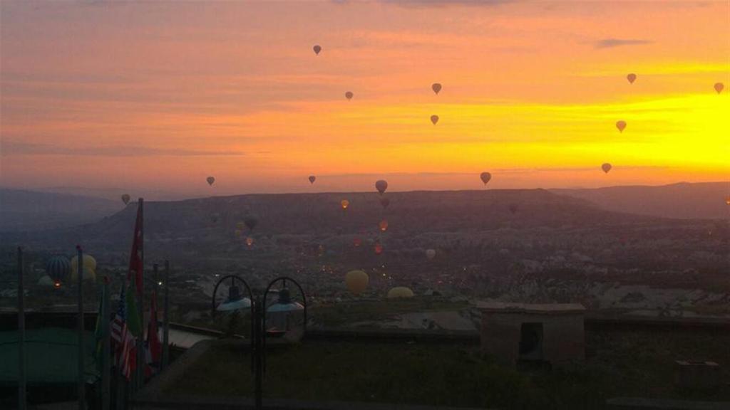 a group of hot air balloons in the sky at sunset at My Cave La Maison Du Reve in Uçhisar
