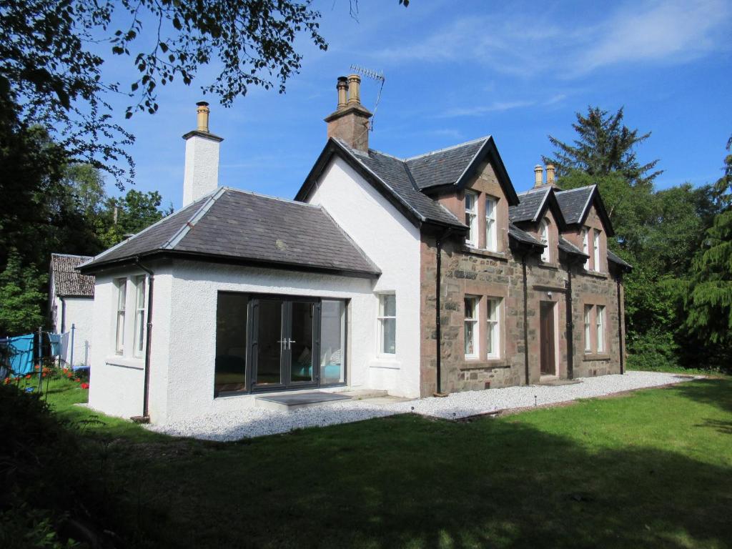une maison ancienne avec une grande fenêtre sur une pelouse dans l'établissement Seawinds, à Kyle of Lochalsh