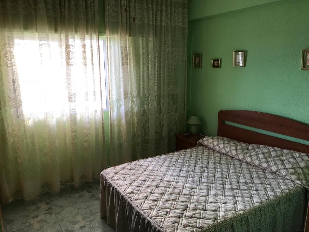 a bedroom with a bed and a window with curtains at Piso ideal para las vacaciones in Miramar