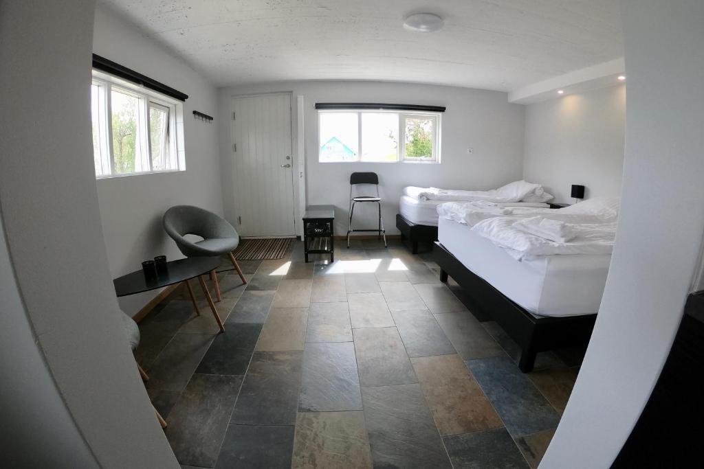 a bedroom with two beds and a desk and two windows at Hamrar in Einarsstaðir