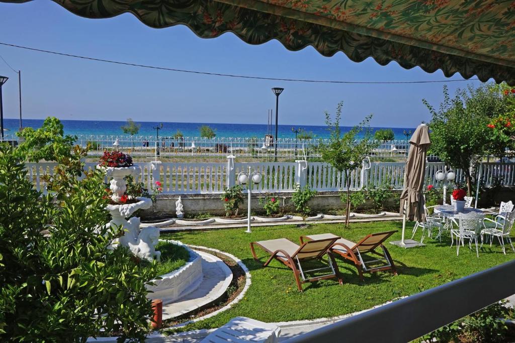 a patio with tables and chairs and the ocean in the background at Villa Fofo - Beautiful Sea Front Villa with 650m2 garden in Nea Kalikratia