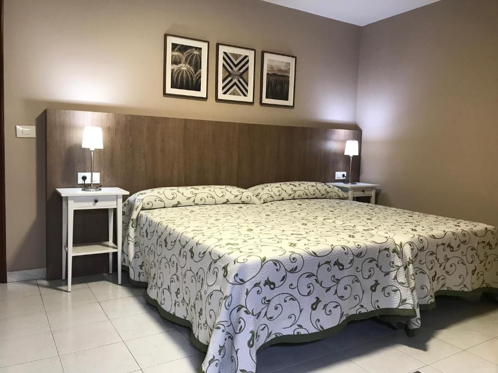 Un dormitorio con una cama grande y dos mesas. en Hostal-Restaurante Paris, en Forcarei