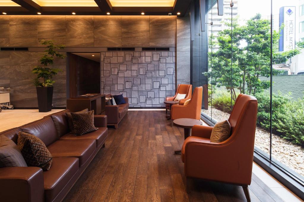 a lobby with leather couches and chairs and large windows at Hotel Mystays Premier Akasaka in Tokyo
