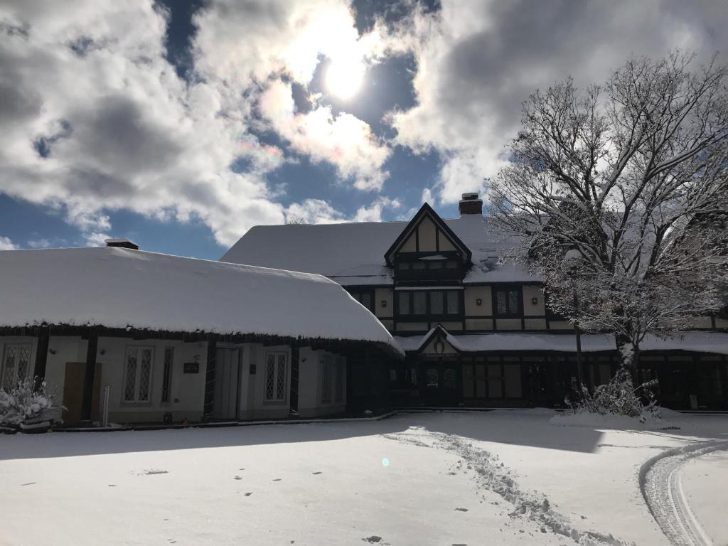 a building covered in snow with the sun in the sky at Shakespeare Hotel in Hakuba