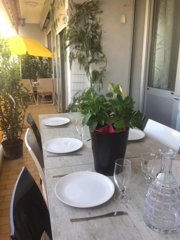a table with plates and glasses and a plant on it at SOPHIES HOMES APARTEMENT BEACH and PROMENADE DES ANGLAIS in Nice