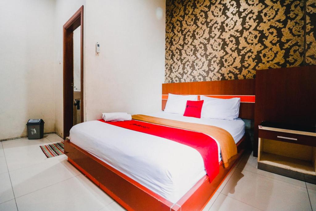 a bedroom with a large bed with red and white sheets at RedDoorz Plus @ Grand City Inn in Makassar