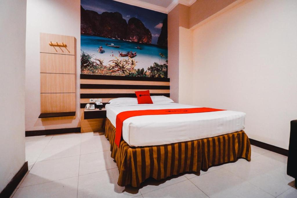 Reddoorz Plus near Makassar Town Square في ماكاسار: غرفة نوم بسرير مع لوحة على الحائط