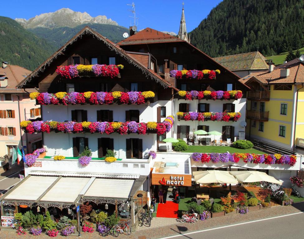 a building with flowers on the balconies in a town at Active Hotel Ancora in Predazzo