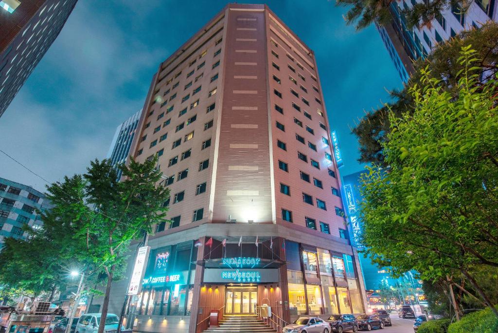 a tall building on a city street at night at New Seoul Hotel Myeongdong in Seoul