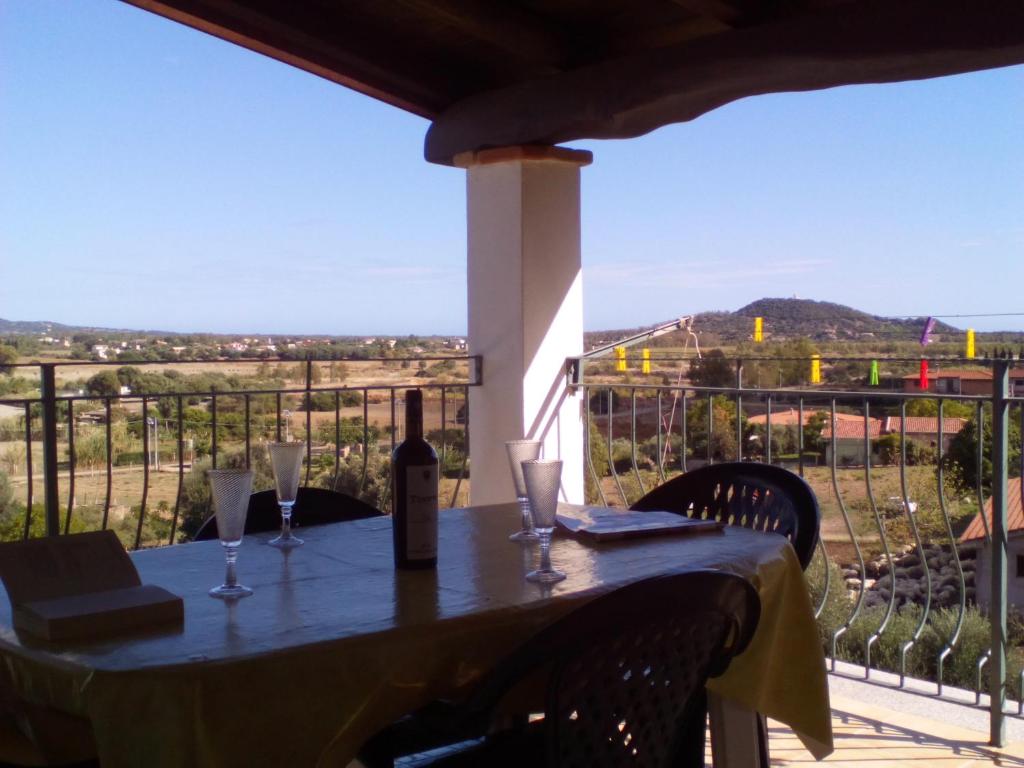 einen Tisch mit einer Flasche Wein und Gläsern auf dem Balkon in der Unterkunft Appartamento MareNatura in Cardedu