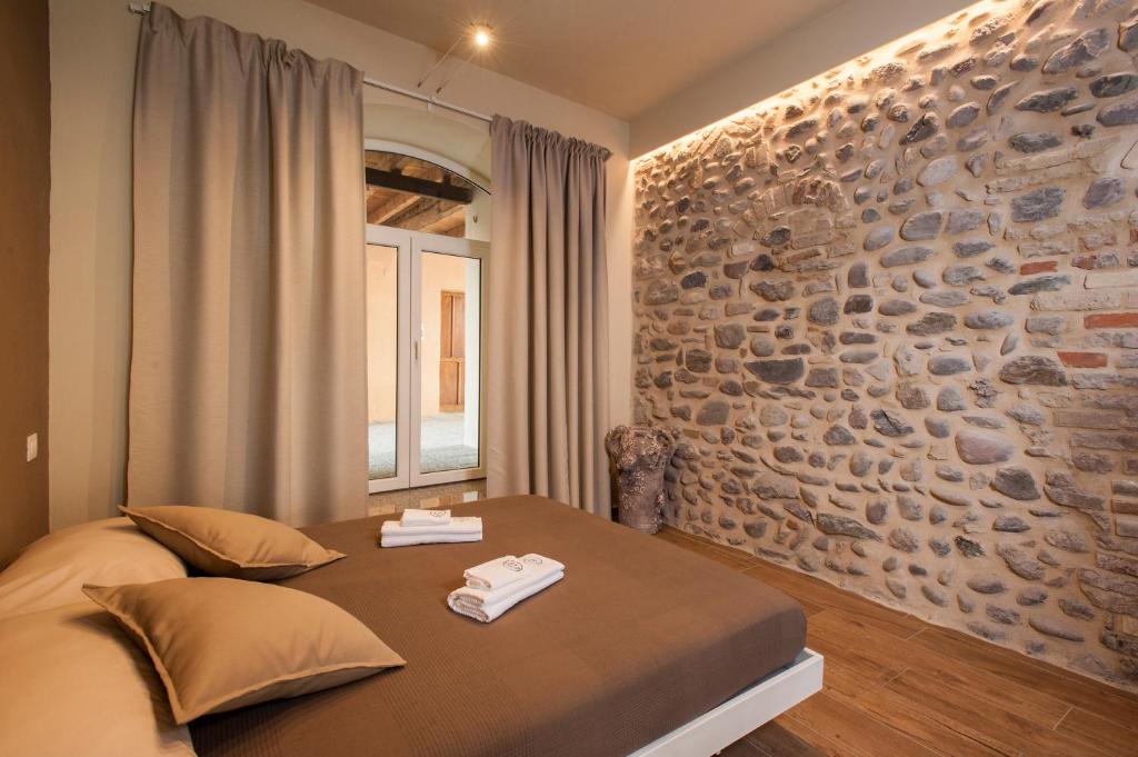 - une chambre avec un lit et un mur en pierre dans l'établissement La Bellavita Del Garda Luxury Apartments, à San Felice del Benaco