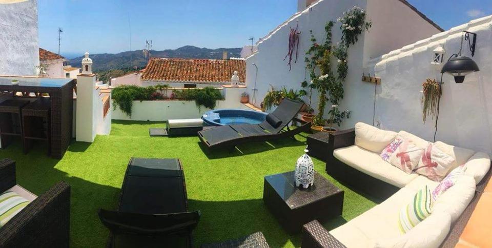 a backyard with a green yard with a couch and chairs at Casa Rural Miller's of Frigiliana in Frigiliana