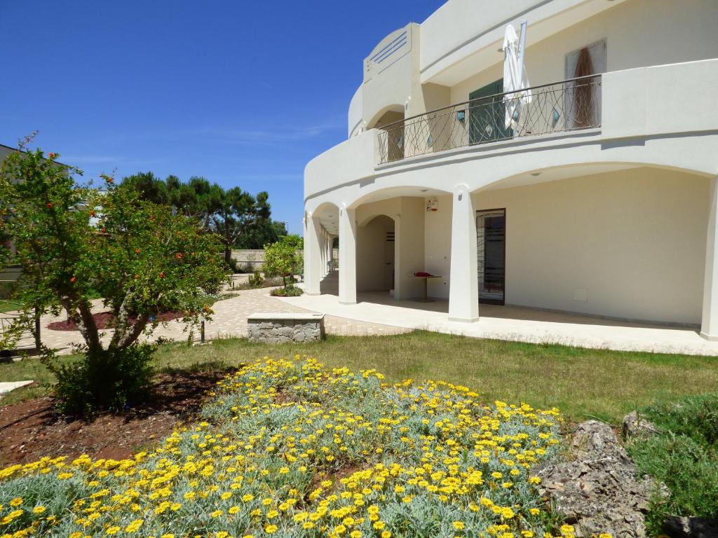 ein weißes Haus mit gelben Blumen im Hof in der Unterkunft Residence Il Colle in Porto Cesareo