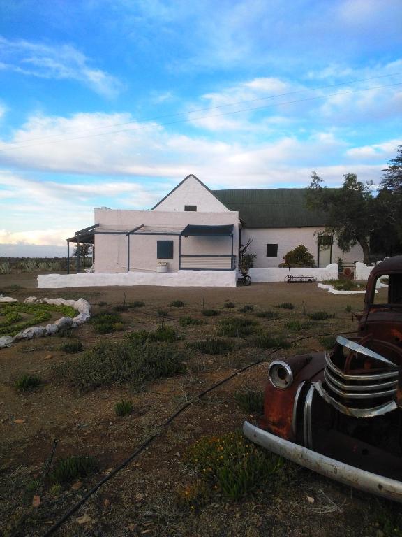 a white house with a truck in front of it at Silwerkaroo Gastehuis in Beaufort West