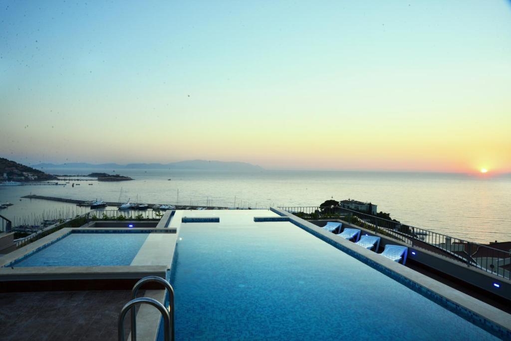 einen Pool mit Blick auf das Meer bei Sonnenuntergang in der Unterkunft Pine City Residence in Kusadası