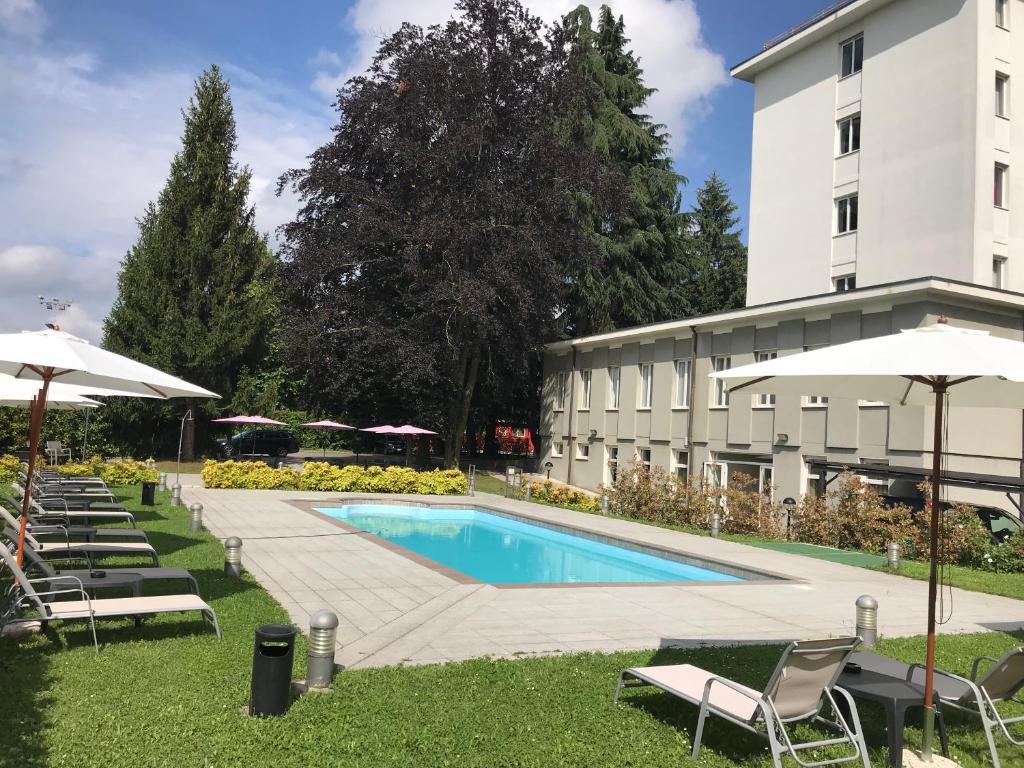 uma piscina em frente a um edifício com cadeiras e guarda-sóis em Bis Hotel Varese em Varese