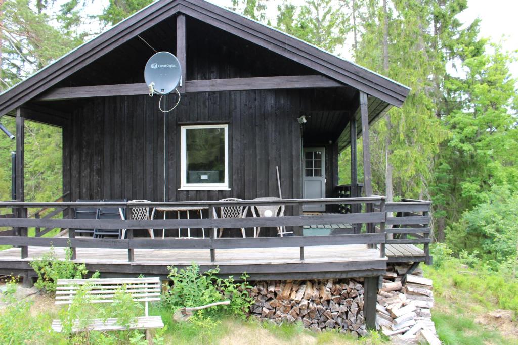 eine schwarze Hütte im Wald mit einer Veranda in der Unterkunft Bergheim Two-Bedroom Cottage in Birkeland