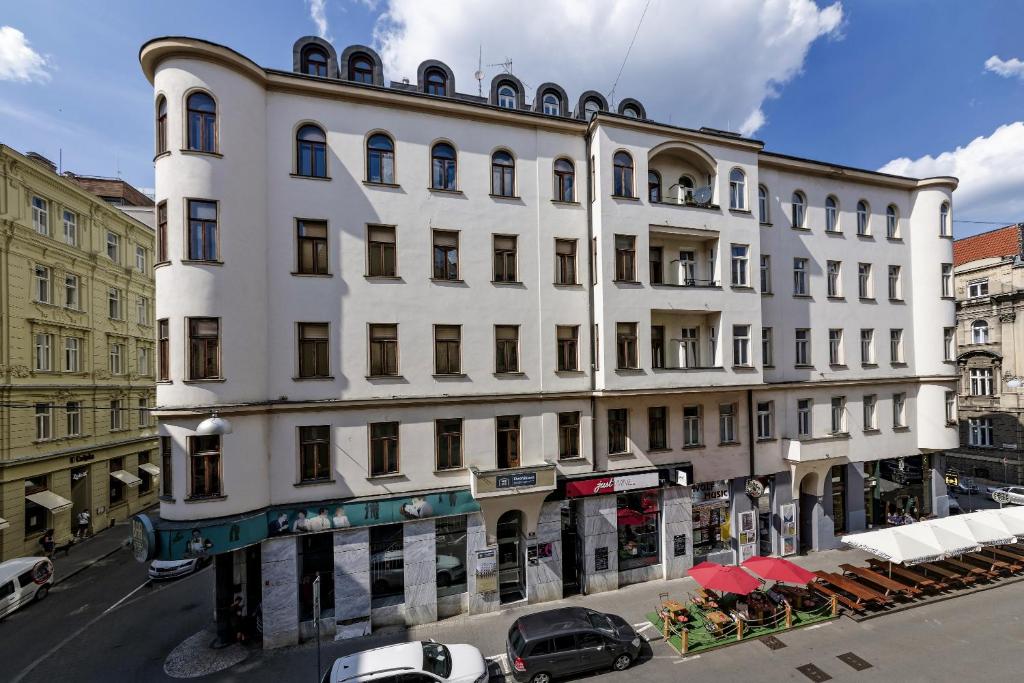 un edificio blanco en una calle con coches aparcados delante en Penzion Dvořákova, en Brno