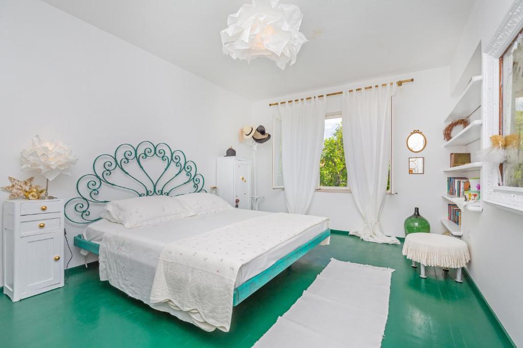 a white bedroom with a bed and a green floor at Apartment and Rooms Lapad in Dubrovnik