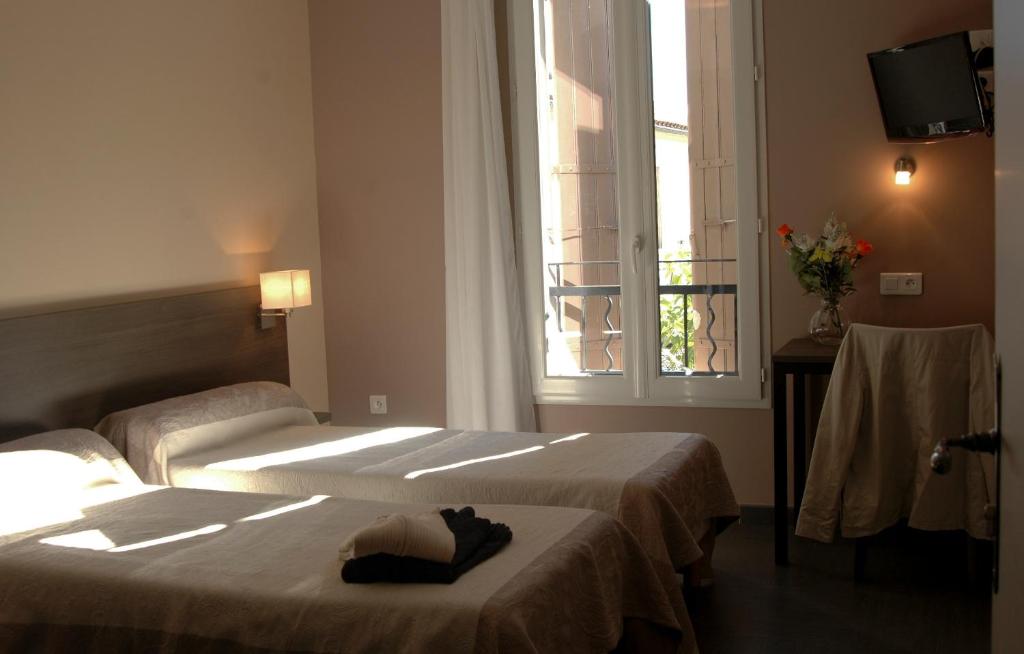 Orgnac-lʼAvenにあるHOTEL RESTAURANT LES STALAGMITESのベッド2台と窓が備わるホテルルームです。