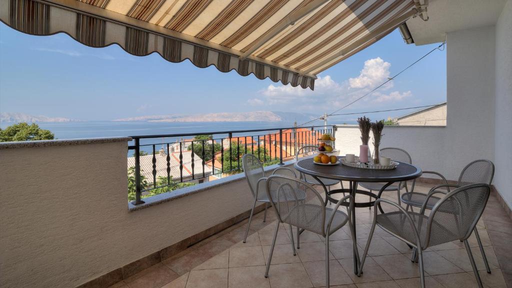 een balkon met een tafel en stoelen en uitzicht op de oceaan bij Apartment Franko in Senj