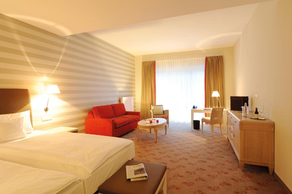 バート・ノイェンアール・アールヴァイラーにあるLandhotel Sanct Peterのベッドと赤い椅子が備わるホテルルームです。