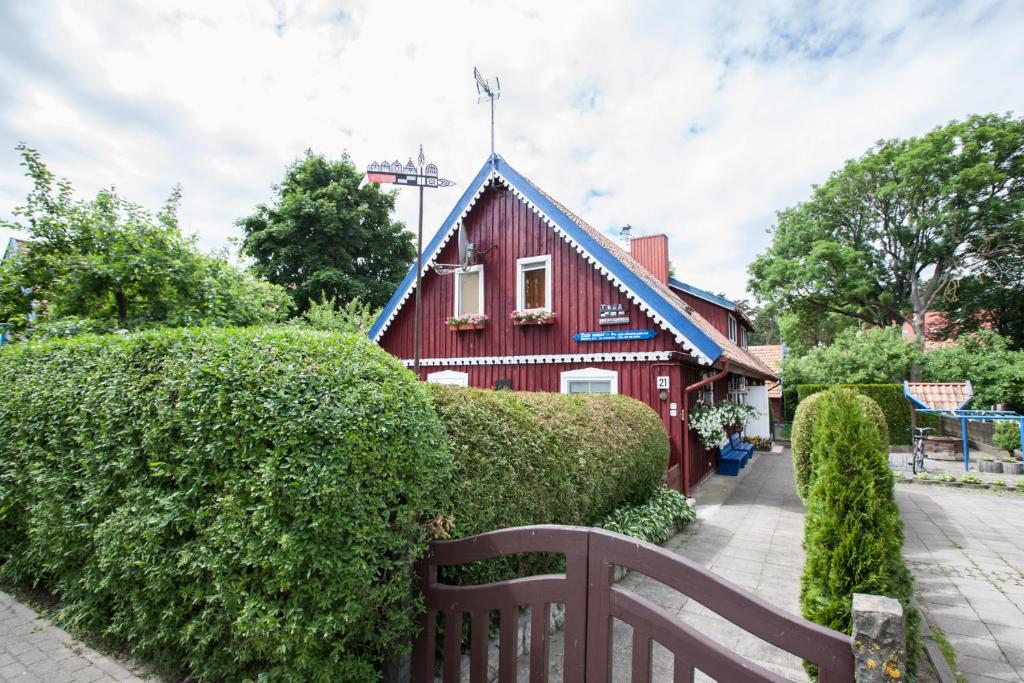 a red house with a blue roof and a bench at Žvejo namas in Nida