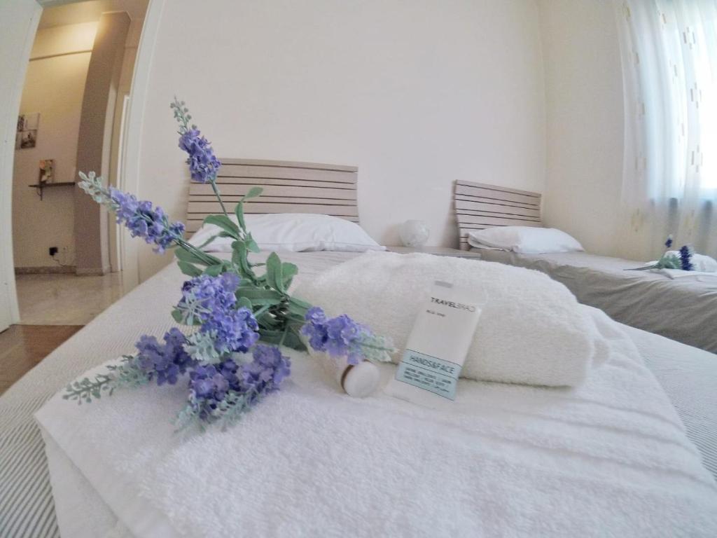 ラ・スペツィアにあるCasa Claudiaの白いベッド(紫色の花束付)