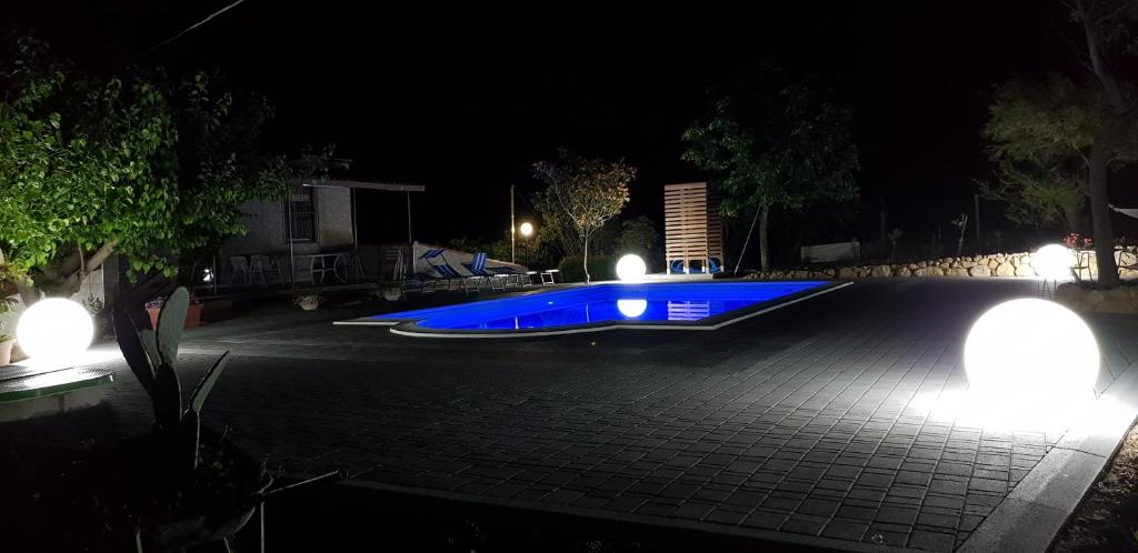 a swimming pool lit up at night with lights at Bed House Floristella in Valguarnera Caropepe