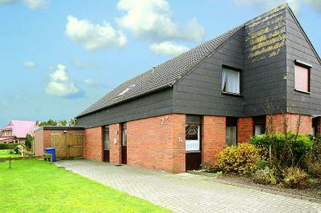 ein rotes Backsteinhaus mit schwarzem Dach in der Unterkunft Haus Nordbrise in Holtgast