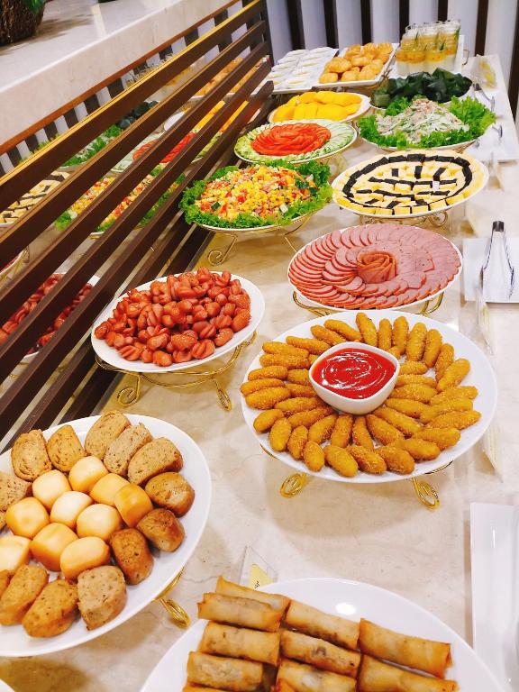 A large buffet spread of breads, fried items, cold cuts, fruit, and salads.