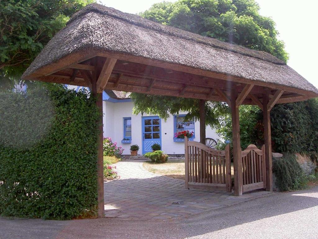 a wooden gazebo with a bench in front of a house at Ferienhaus Diekelmann _ Objekt 258 in Diedrichshagen