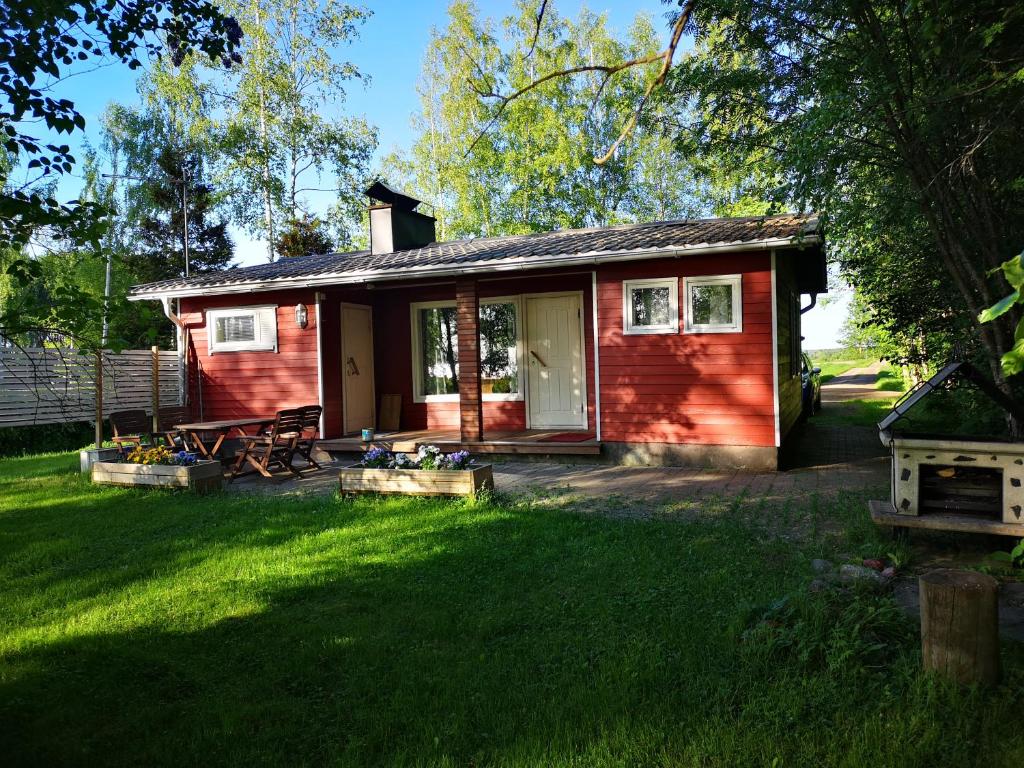 una pequeña casa roja con un patio y césped en Koivuniemi Cottage en Säkylä