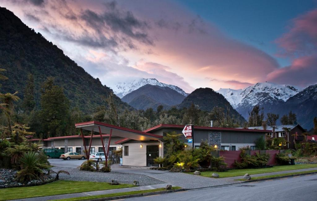 a gas station with mountains in the background at 58 On Cron Motel in Franz Josef
