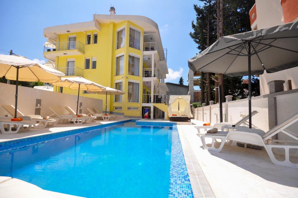 a pool with chairs and umbrellas next to a building at Villa Medusa Apartments in Dobra Voda