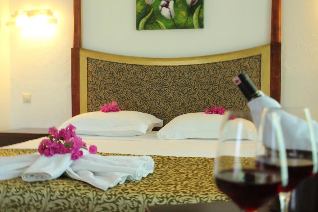 a hotel room with a bed with towels and a bottle of wine at Hotel Ekincik in Ekincik