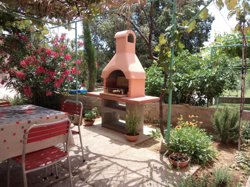 a patio with a pizza oven in a garden at Jandric Apartments in Lopar