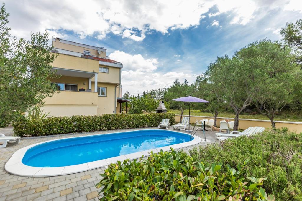 a swimming pool in front of a house at Apartments Villa Orion in Kožino