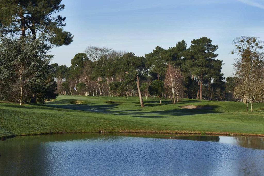a golf course with a pond in the foreground at Chambres Élégance - Parc Bordelais in Bordeaux