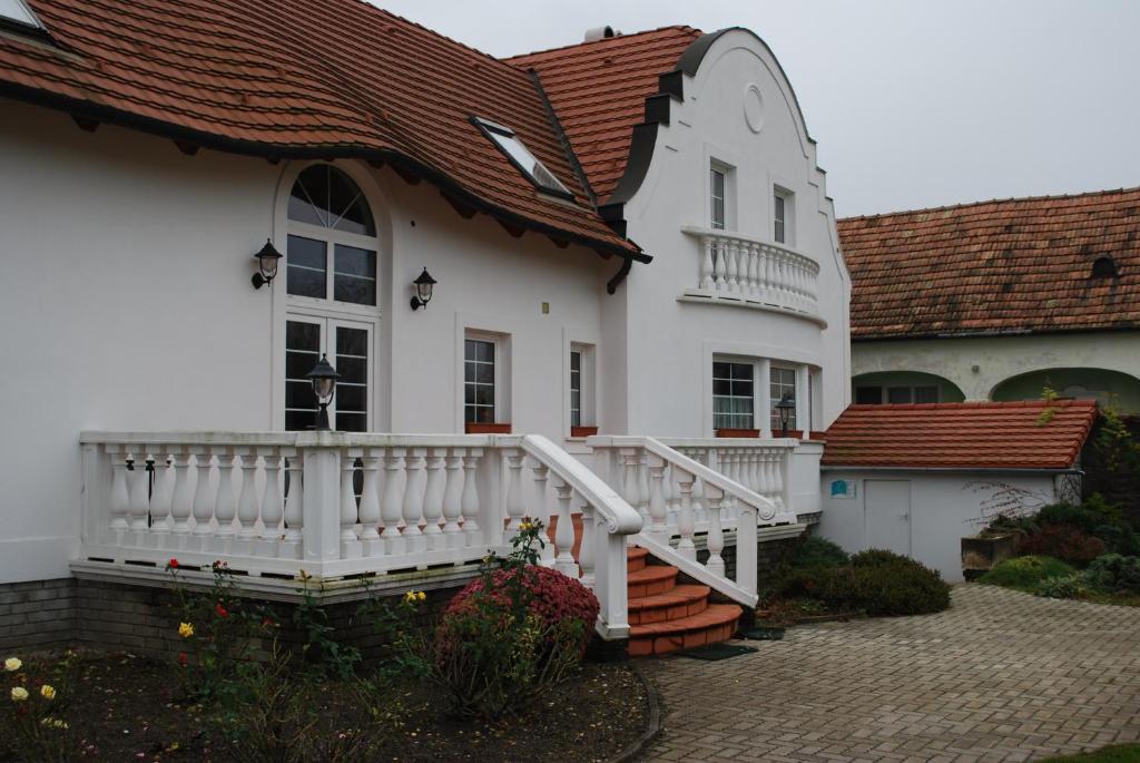 a white house with a porch and a balcony at Rozália Vendégház in Sarród