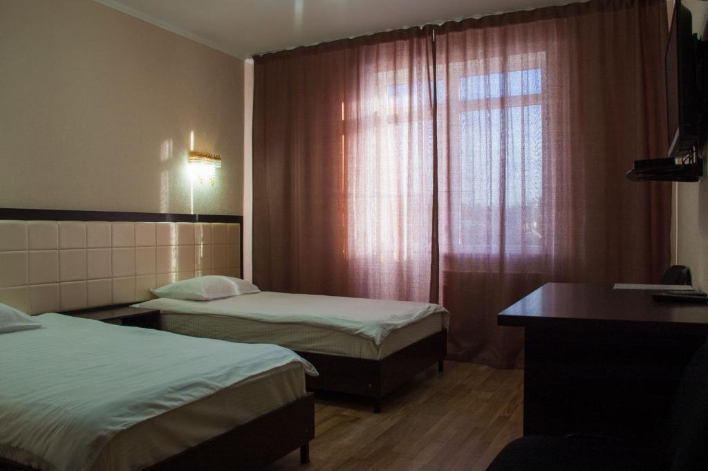 a hotel room with two beds and a window at Altamira Hotel in Karakol