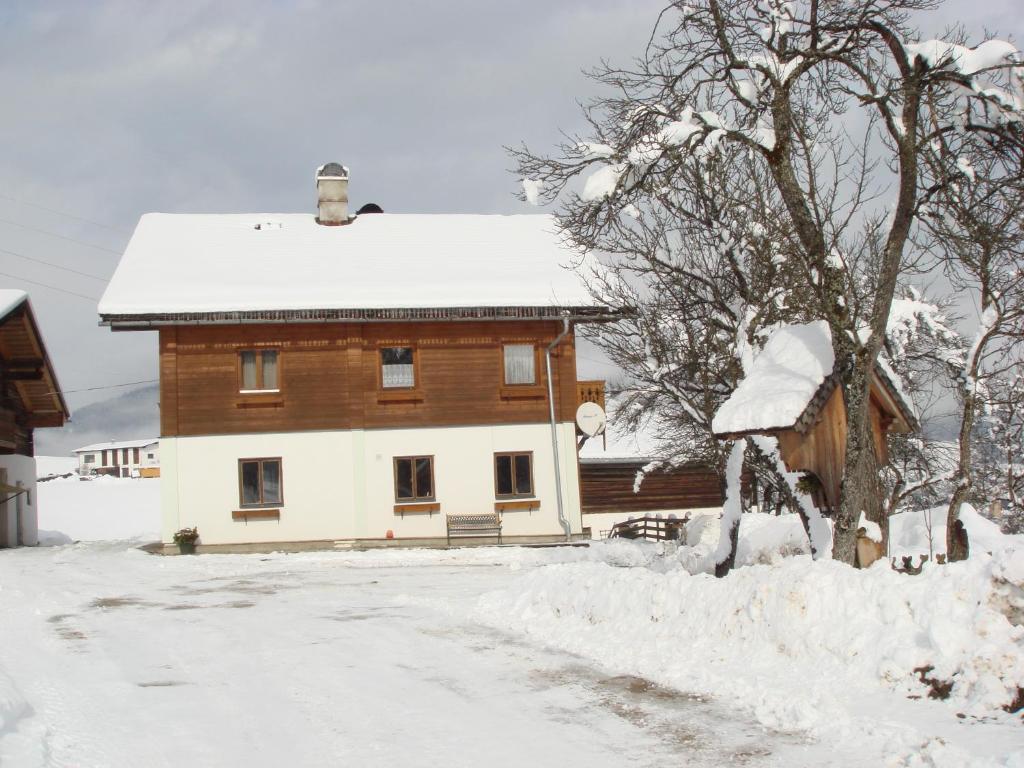 a snow covered house with a tree in front of it at Brandstättgut in Altenmarkt im Pongau