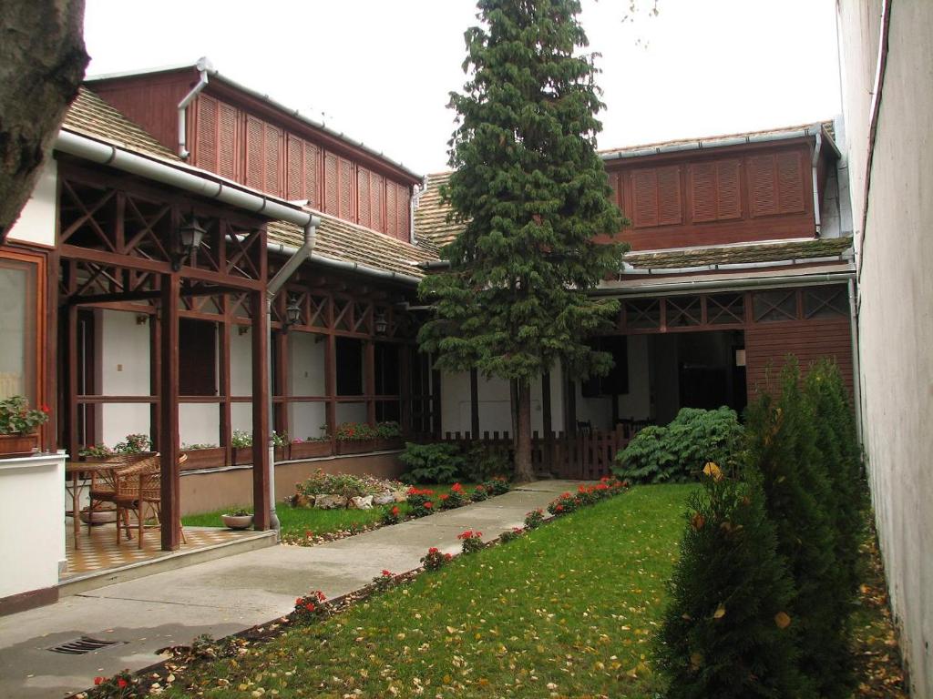 a courtyard of a building with a tree in the yard at Hotel Fama in Hódmezővásárhely