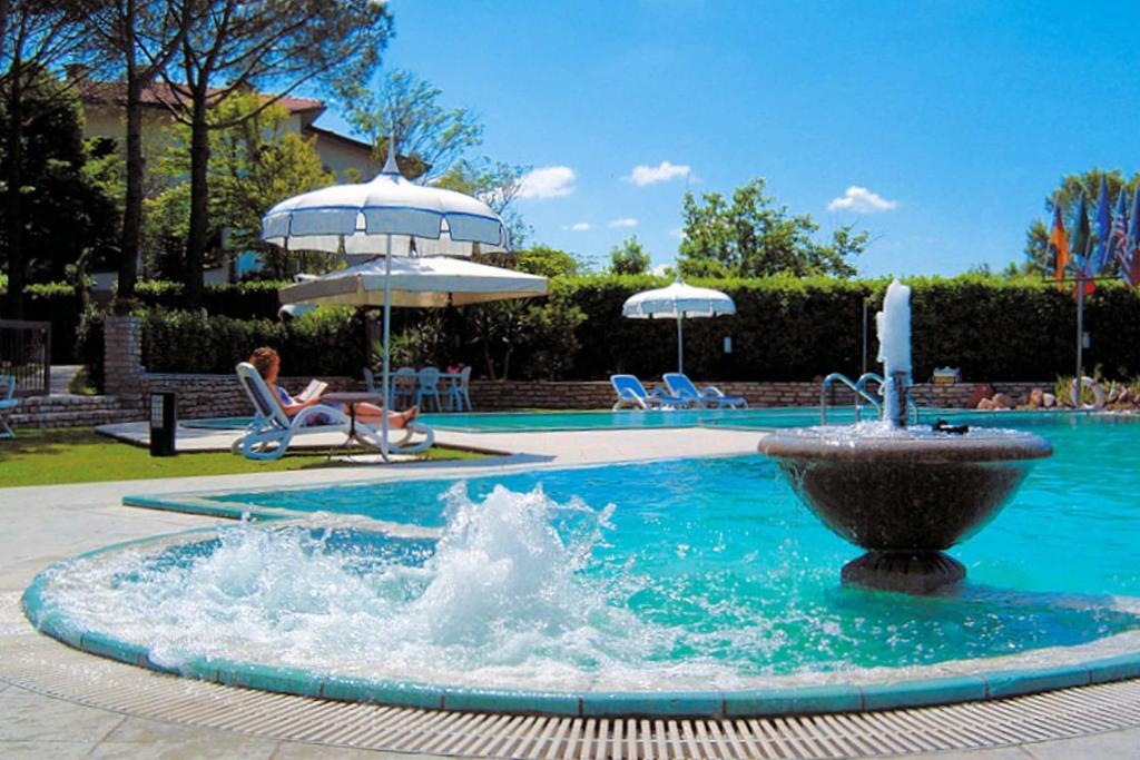 una fontana al centro di una piscina con ombrelloni di Villa Rossana a Cenaia