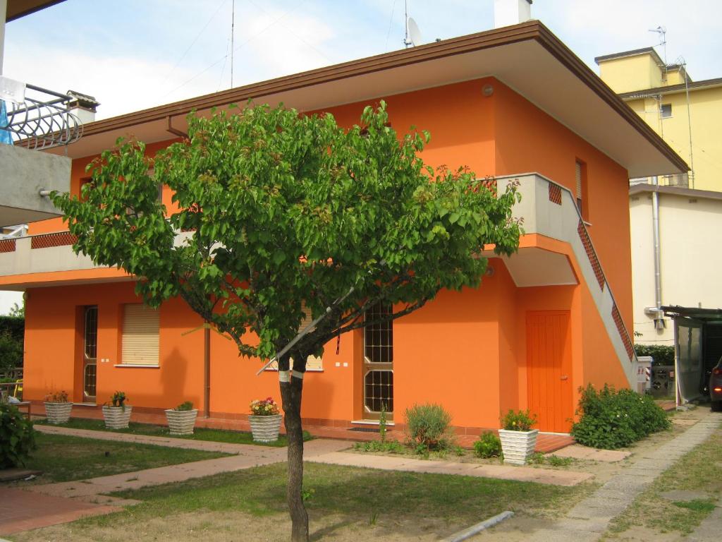 una casa naranja con un árbol delante de ella en Flavia Flats, en Bibione