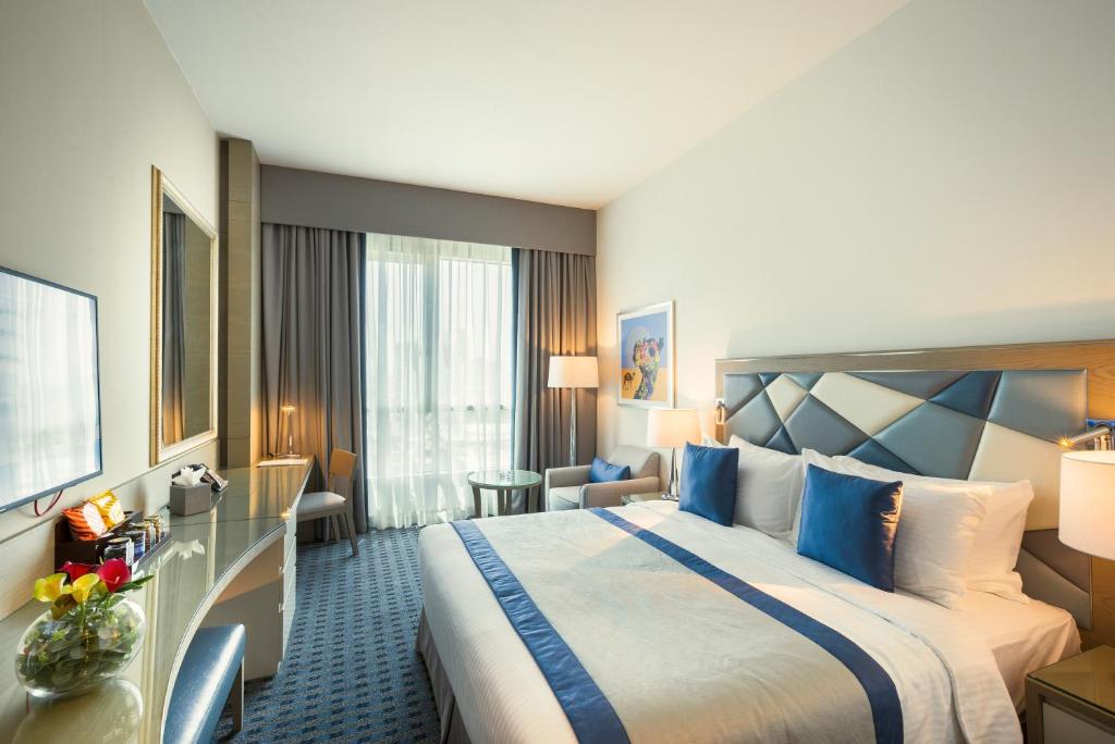 a hotel room with a large bed with blue accents at Gulf Inn Hotel Al Nasr Formerly Roda Links Al Nasr in Dubai