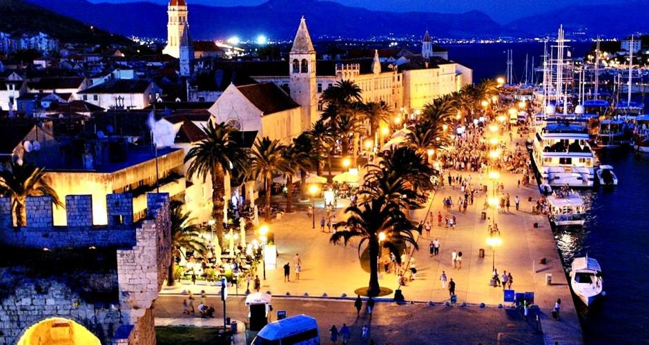 eine Stadt in der Nacht mit Palmen und einem Hafen in der Unterkunft Apartments Naomi and Marsel in Trogir