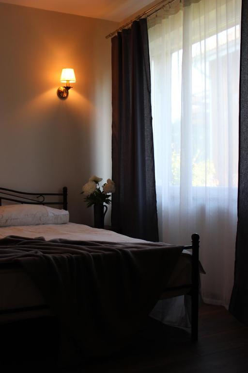 Un dormitorio con una cama y una ventana con cortinas. en Old Willows, en Ventspils