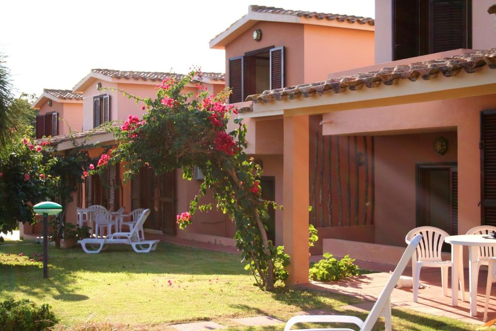 a house with a yard with white chairs and pink flowers at Verdemare Sardegna Due Villette in Villasimius