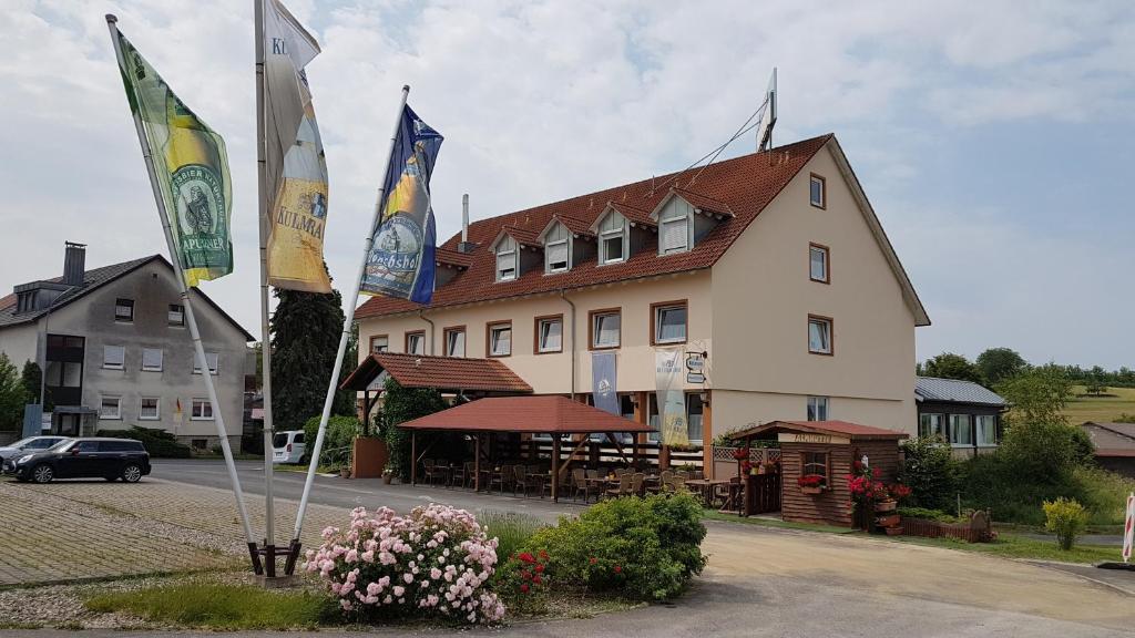 un bâtiment avec trois drapeaux devant lui dans l'établissement Landgasthof Frankentor, à Wasserlosen